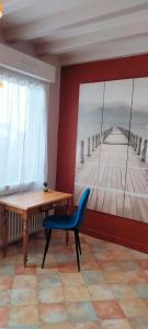 a room with a table and a blue chair and a painting at Entre vigne et Loire in La Coindassière