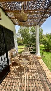 a wooden deck with two chairs and a table and aicker umbrella at Villa Riad Ambre in Douar bel Rhanodour