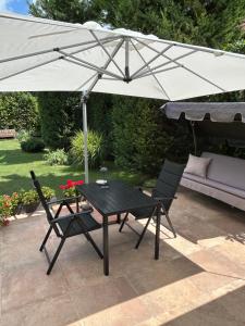 a black table and two chairs under an umbrella at CSAOL Apartman ház in Velence