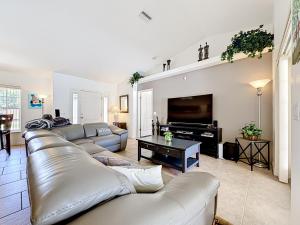 a living room with a leather couch and a television at 3BR Home Trailside Pool & Jacuzzi, Minutes from Inverness, Ocala & Crystal River in Inverness