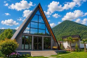 a house with a triangular roof with a mountain in the background at Area36 Family Chalet in Gabala