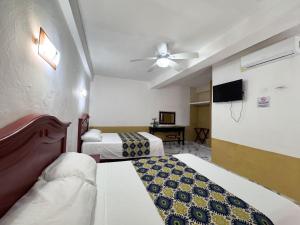 a hotel room with two beds and a ceiling fan at Hotel Santa Ana in Valladolid