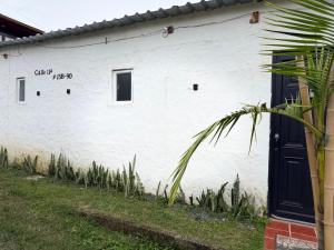 a white building with a black door and a plant at Villa campestre Las Palmas in Calima