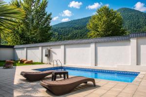 a swimming pool with two benches next to a building at Area36 Family Chalet in Gabala
