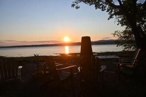 a sunset over a body of water with chairs at VILLA-29 Spa, Sauna, Sunset & Waterfront View in Sainte-Petronille