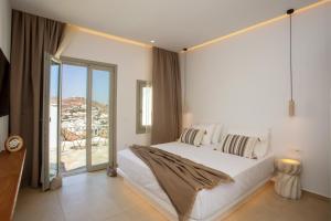 a bedroom with a large white bed and a balcony at Stilvi Mykonos in Ornos
