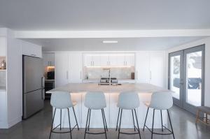 a kitchen with a large island with four chairs at VILLA-29 Spa, Sauna, Sunset & Waterfront View in Sainte-Petronille