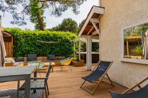 a patio with a table and chairs on a wooden deck at maison familiale à 2 pas du lac,avec spa, à la Gde Escoure-grives in Lacanau