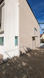 a white building with a shadow on the side of it at Mansion with Swimming Pool, Pool Table & GrillArea in Braga