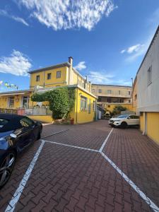 a parking lot with two cars parked in front of a yellow building at Nuova Aurora in Marghera