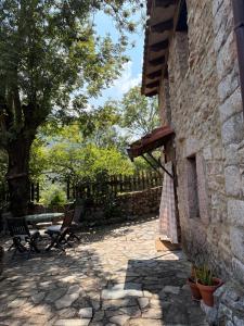 a stone patio with two chairs and a tree at La aldea de lug in Rozagás