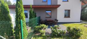 a house with a fence and a table and chairs at Apartament Przylesie 2 in Stężyca