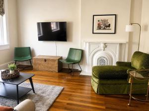 a living room with a green couch and chairs at Modern Main Street Charm in Georgetown