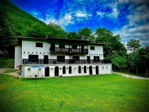 a large white house with a green field in front of it at La Izvoare in Clopotiva