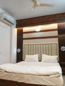 a bedroom with a large white bed with a wooden headboard at Orange Elite Stays Whitefield in Bangalore