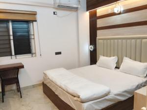 a bedroom with a bed and a desk and window at Orange Elite Stays Whitefield in Bangalore