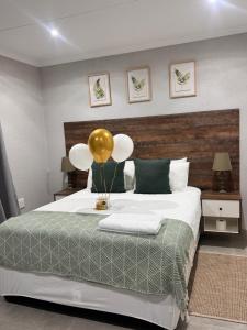 a bedroom with a bed with a gold balloon on it at Phumlani Village Lodge in White River