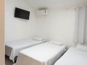 a white room with three beds and a tv at Studios Congresso suites e Lofts Duplex in Brasília