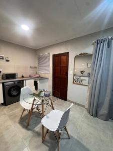 a kitchen with a table and white chairs in a room at Phumlani Village Lodge in White River
