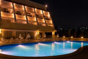 a swimming pool in front of a building at night at chalet in Saint remon in Al ‘Ayn +5 photos