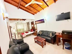 a living room with leather furniture and a flat screen tv at Happy Night Holiday Inn in Unawatuna