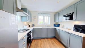 a kitchen with blue cabinets and a sink at Ocean Cove - Part of the The Bay Filey Holiday Village with pool, gym and direct beach access, pub, restaurant, tennis and meadows walks in Reighton