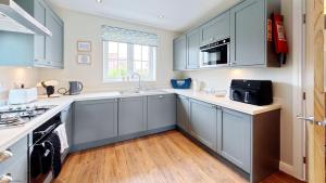 a kitchen with blue cabinets and a sink at Ocean Cove - Part of the The Bay Filey Holiday Village with pool, gym and direct beach access, pub, restaurant, tennis and meadows walks in Reighton +42 photos