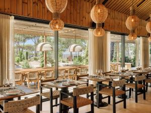 a dining room with tables and chairs and large windows at Sublime Comporta in Comporta