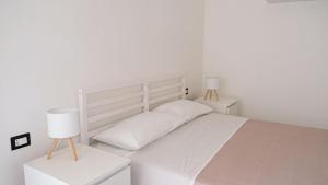 a white bedroom with a white bed and two night stands at Aura Apartments in Pompei