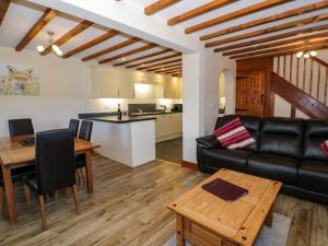 a living room with a black leather couch and a table at Cornel Clyd in Llanddulas