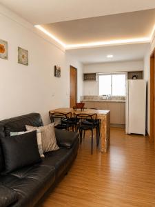 a living room with a couch and a table and a refrigerator at Flat com Jacuzzi - Cantinho do Lago 2 in Capitólio