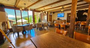 a dining room with tables and chairs and windows at Alpine Castle Hotel in Dilijan