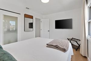 a white bedroom with a bed and a flat screen tv at LA Gramercy in Los Angeles