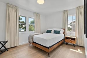 a white bedroom with a bed and two windows at LA Gramercy in Los Angeles
