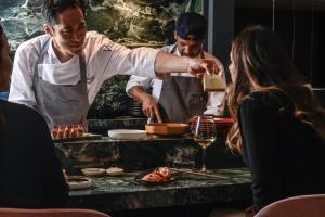 a chef preparing food on a table in a restaurant at Sina De La Ville in Milan