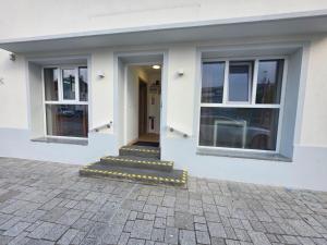 a white building with two windows and a staircase at Chambres mimi deni in Hésingue