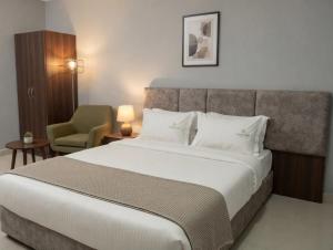 a bedroom with a large bed and a chair at Hotel Rise Grand Kukatpally Near Hitex Exhibition Center & Nexus Mall, Yashoda Hospital in Hyderabad
