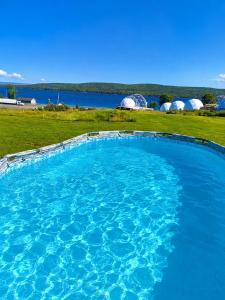 a large pool of blue water with tents in the background at Baddeck Domes in Baddeck