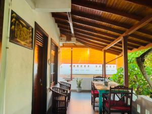 a dining room with a table and chairs on a porch at Happy Night Holiday Inn in Unawatuna