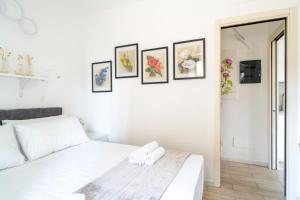 a bedroom with a white bed and framed pictures on the wall at Pepita del Lago - Piscina e Parcheggio privato in Lenno +18 photos