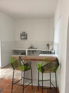 a kitchen with two green chairs and a counter at Casa Natus Hostal in Zapatoca