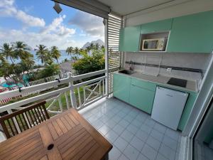 a kitchen with a balcony with a view of the ocean at Ti Dyaman - Studio vue mer & accès piscine gratuit in Le Diamant