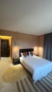 a bedroom with a large white bed and a rug at Villa Riad Ambre in Douar bel Rhanodour +39 photos