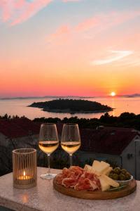a plate of food and two glasses of wine on a table with the sunset at Apartments Tonći and Iris in Primošten +26 photos