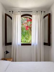 a bedroom with a bed and a window with white curtains at Villa Florineth in Simius