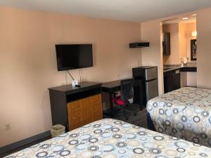 a hotel room with two beds and a desk with a television at Paradise Inn & Suites in Baton Rouge