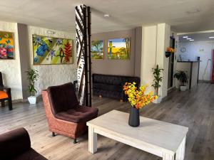 a living room with a chair and a table with flowers at Hotel Las Flores in Santa Rosa de Cabal