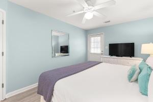 a bedroom with a white bed and a flat screen tv at Atlantic Sunrise in Tybee Island