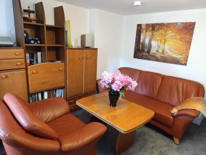a living room with a couch and a table with flowers at Ferienhof Saalendorf in Großschönau