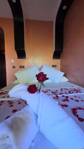 a bed with two roses sitting on top of it at HOTEL RESTAURANT LA KaSBAH in Tinerhir